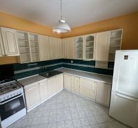 A kitchen in a family house with cream cabinets, dark green tiles, and a white appliance.
