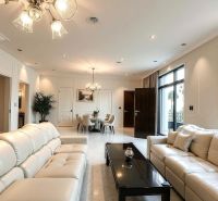 Interior of a family house with cream sofas, a black table, and plants.