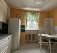 A kitchen in a family house with white furniture, a refrigerator, and a table for two people.