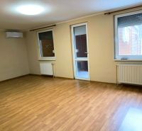 A spacious room in a family house with a wooden decor floor and windows.