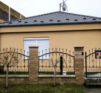 A family house in Ohrady with a stone fence and a satellite dish on the roof.