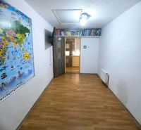 A room in a family house with a wooden decor floor, a map on the wall, and a bookshelf with books.