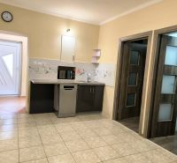 A kitchen in a family house with light-colored tiles and a kitchen unit with a microwave.