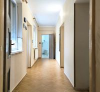 A hallway in a family house with ceramic tiles and light-colored walls.