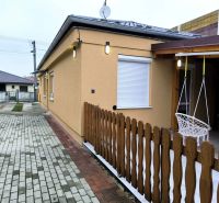 A family house in Ohrady with a courtyard, fencing, and a hanging swing by the side entrance.