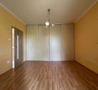 A room in a one-room apartment with a wooden decor floor and built-in wardrobes.