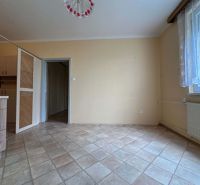 Interior of a 1-room apartment with a beige wall and tiled floor.