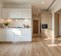 A kitchen in a studio apartment with a wood-patterned floor and white cabinets.