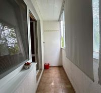 A narrow loggia with flowers and blinds in a one-room apartment, a floor with a stone decor.