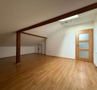 Attic room in a 3-room apartment with a wooden decor floor and wooden beams.