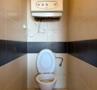 A toilet with tiles and a water heater in a 3-room apartment.
