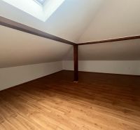 An attic room with a wooden decor floor and a skylight in a 3-room apartment.
