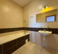 The bathroom with a bathtub in the 3-room apartment has light tiles and a mirror above the sink.