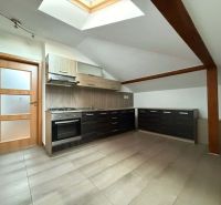 A kitchen in the attic of a 3-room apartment with dark cabinets and a skylight.
