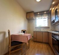 A kitchen in a 3-room apartment with a wooden decor floor and a dining table.