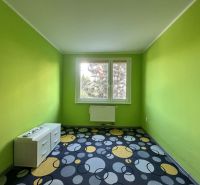 A room in a 3-room apartment with a colorful carpet and green walls.