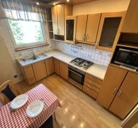 A kitchen with a wooden decor floor and a dining table in a three-room apartment.