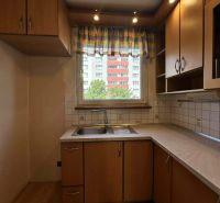 A kitchen with a wood-patterned floor in a 3-room apartment, simple kitchen cabinets.