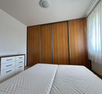 A bedroom with a wardrobe featuring a wooden decor and a dresser in a three-room apartment.