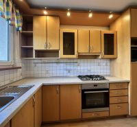 A kitchen in a 3-room apartment with wooden cabinets and white tiles.