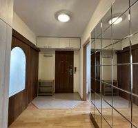 Entrance hall of a 3-room apartment with a wooden decor floor and a mirrored wall.