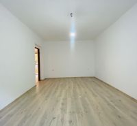 A spacious room with white walls and a floor with a wooden decor in a studio apartment.