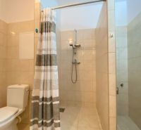 Bathroom in a studio apartment with a bathtub, tiles, and a curtain.