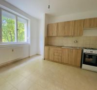 A kitchen in a one-room apartment with a window, a kitchen unit, and a gas stove.