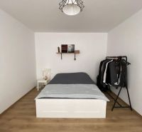 A bedroom in a one-room apartment with a bed, a shelf, and a floor with a wooden decor.