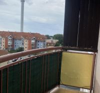 A balcony with a view of apartment buildings and a chimney in Dunajská Streda.