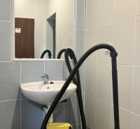 Interior of commercial premises with a sink, mirror, and vacuum cleaner in the room.