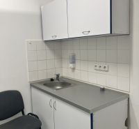 Kitchen corner in commercial premises with white cabinets and a sink.