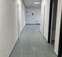 A corridor in commercial premises with white walls and a tiled floor.