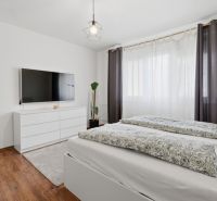 Bedroom in a 3-room apartment with a wood-decor floor, a television, and a dresser.