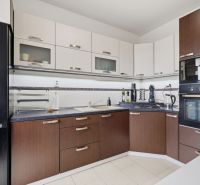 A kitchen in a 3-room apartment with dark furniture and built-in appliances.
