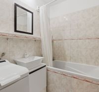 Bathroom with a bathtub, sink, and washing machine in a 3-room apartment.