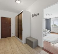 Entrance hallway with tiles, wardrobes, leads to a living room with a wooden decor floor.