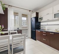 A kitchen in a 3-room apartment with dark furniture and a dining table.