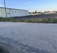 Road and adjacent residential plots in Holice, visible warehouse building.