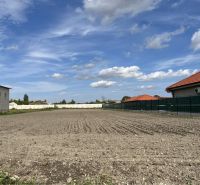 Plots - housing in Holice, between houses with red roofs and blue sky.