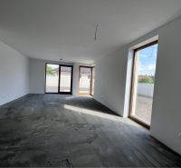 A spacious room with a concrete floor and large windows in a family house.