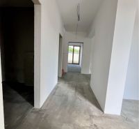 A hallway in a family house with smooth white walls and an unfinished floor.