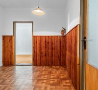A hallway in a 3-room apartment with a wooden decor floor and wooden wall paneling.
