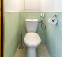 A toilet with green tiles in a 3-room apartment.