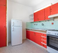 A kitchen in a 3-room apartment with red cabinets and a refrigerator.