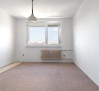 An empty room with a carpet, radiator, window, and pendant light in a 3-room apartment.