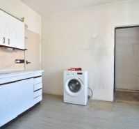 A kitchen in a 3-room apartment with a washing machine and a kitchen unit.