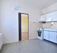 A kitchen in a 3-room apartment with a white kitchen unit and a combination stove.