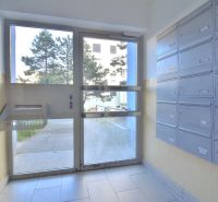 Apartment entrance with mailboxes, view of the outside walkway and trees.