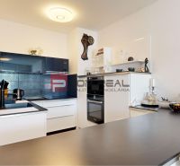 A kitchen in a 2-room apartment with built-in appliances and decorative wall clocks.